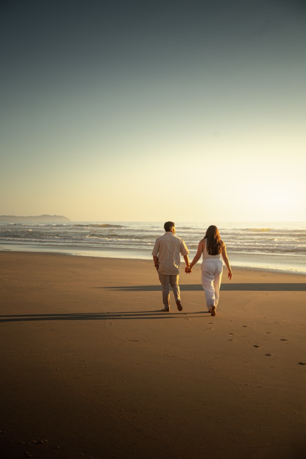 Couple walking hand in hand along the beach at sunset
