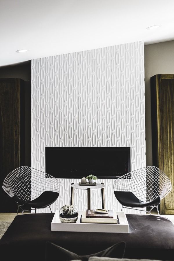 Modern interior — sculpted fireplace wall with wire chairs