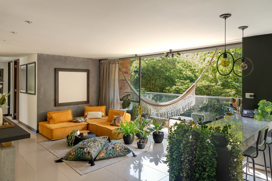 Sunlit living room opening to a balcony with a hammock and plants