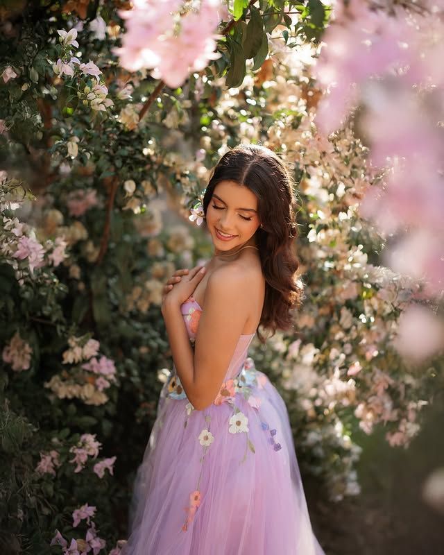 Quinceañera in a lilac floral gown among spring blossoms