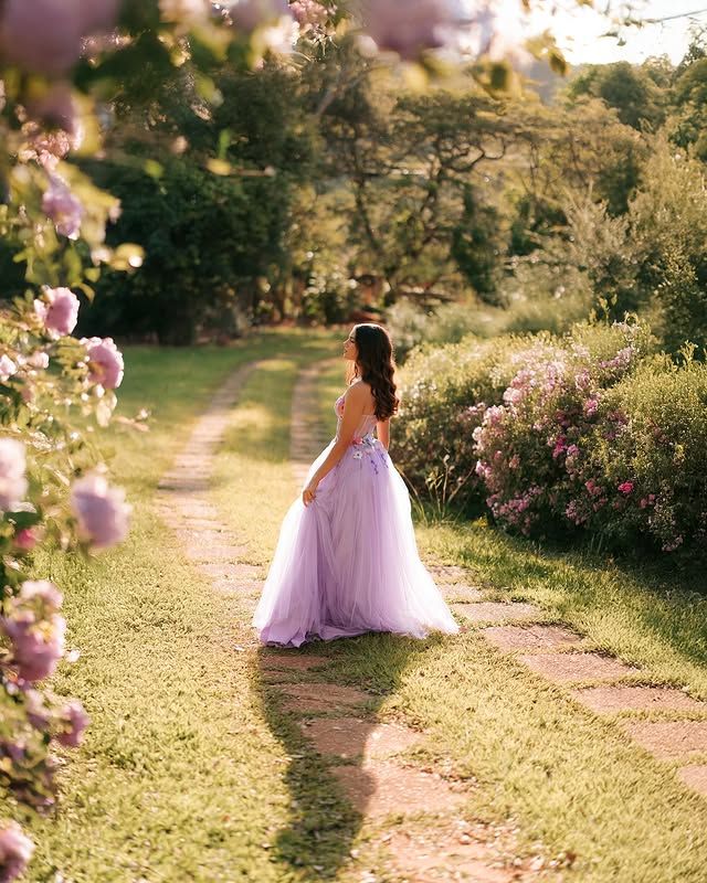 Quinceañera in a lilac tulle gown on a sunlit garden path