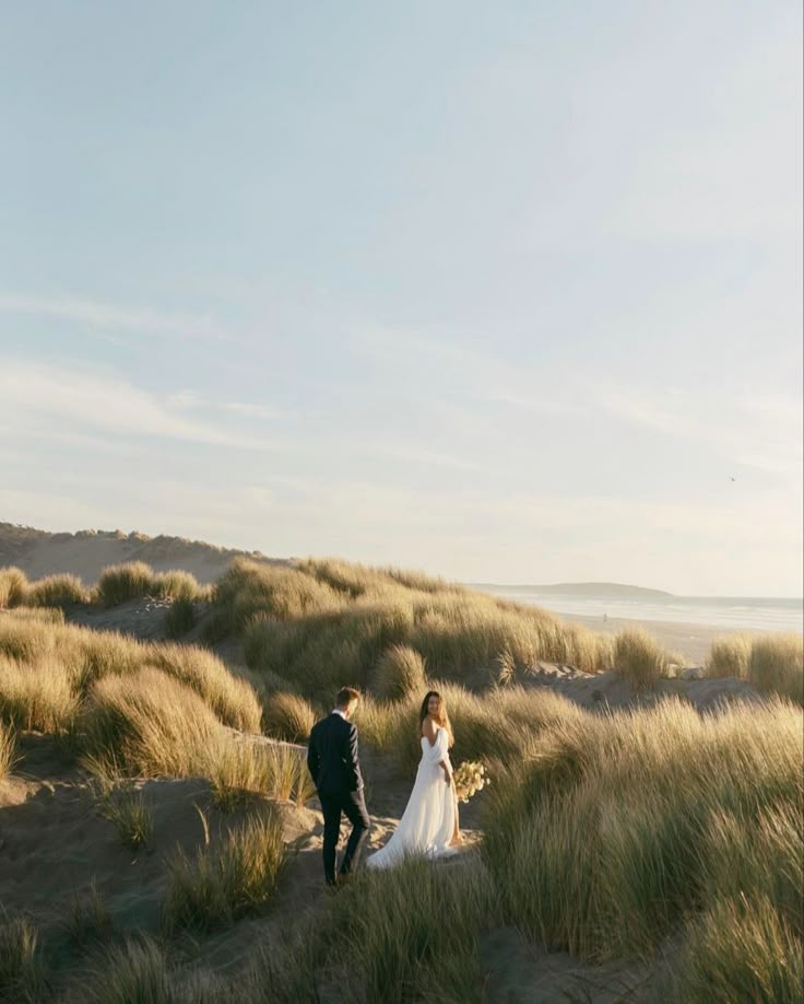 Bride and groom in coastal dune grass at golden hour